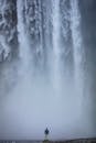 Man Standing under Monumental Waterfall