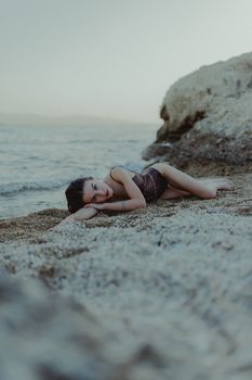 A woman in swimwear lying on a rocky beach, enjoying the summer vibe.