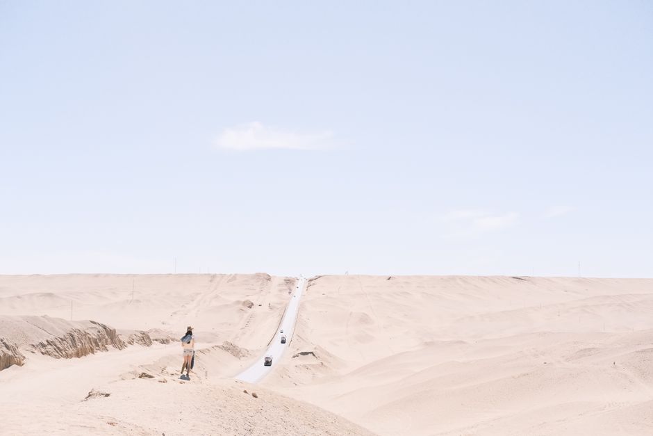 Expansive desert landscape with a solitary road leading towards the horizon under a bright sky.