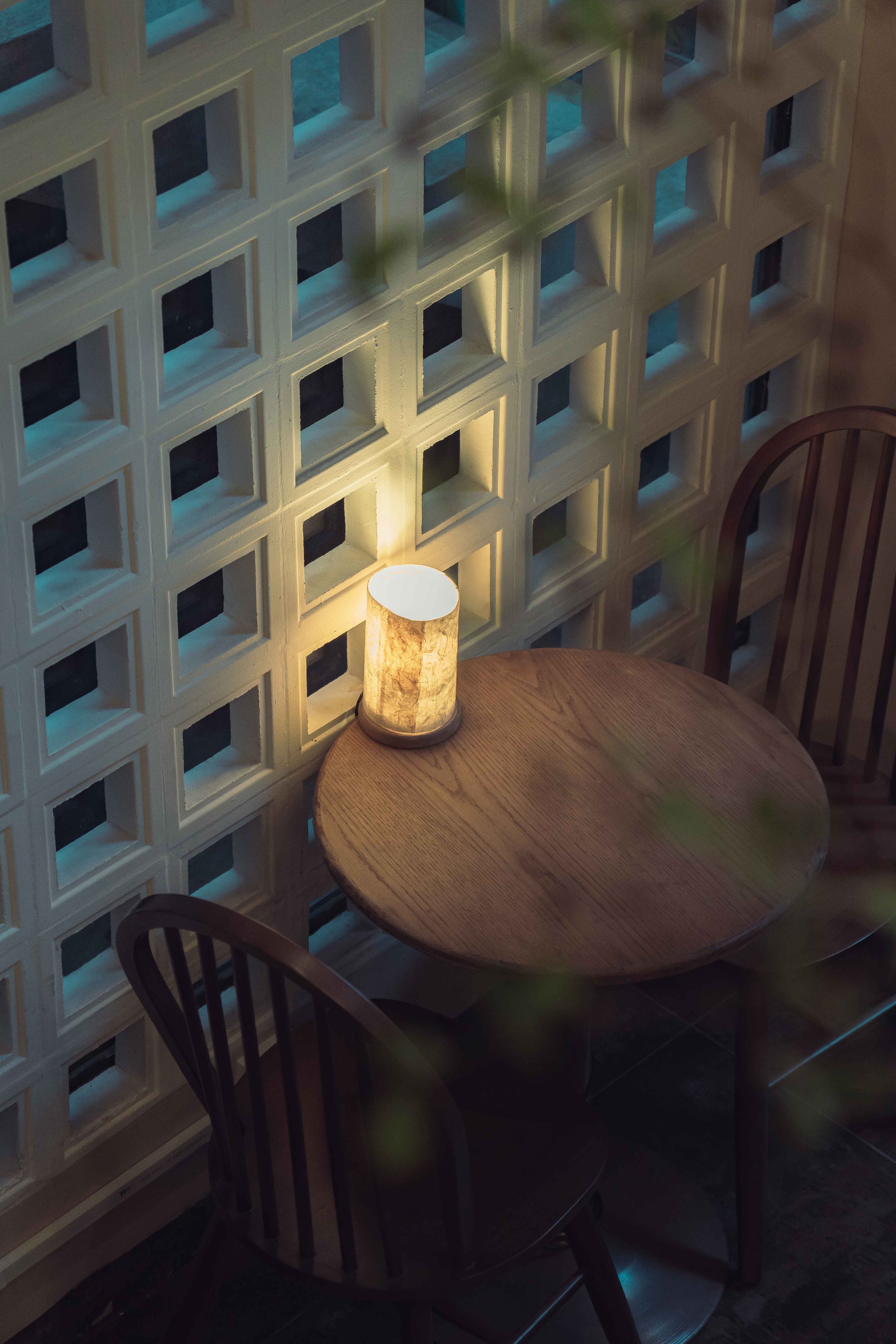 Warm and inviting cafe corner in Ho Chi Minh City with soft lamp light on a wooden table.