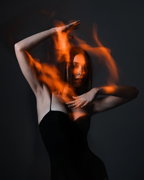 A woman in a black dress with fire in her hands