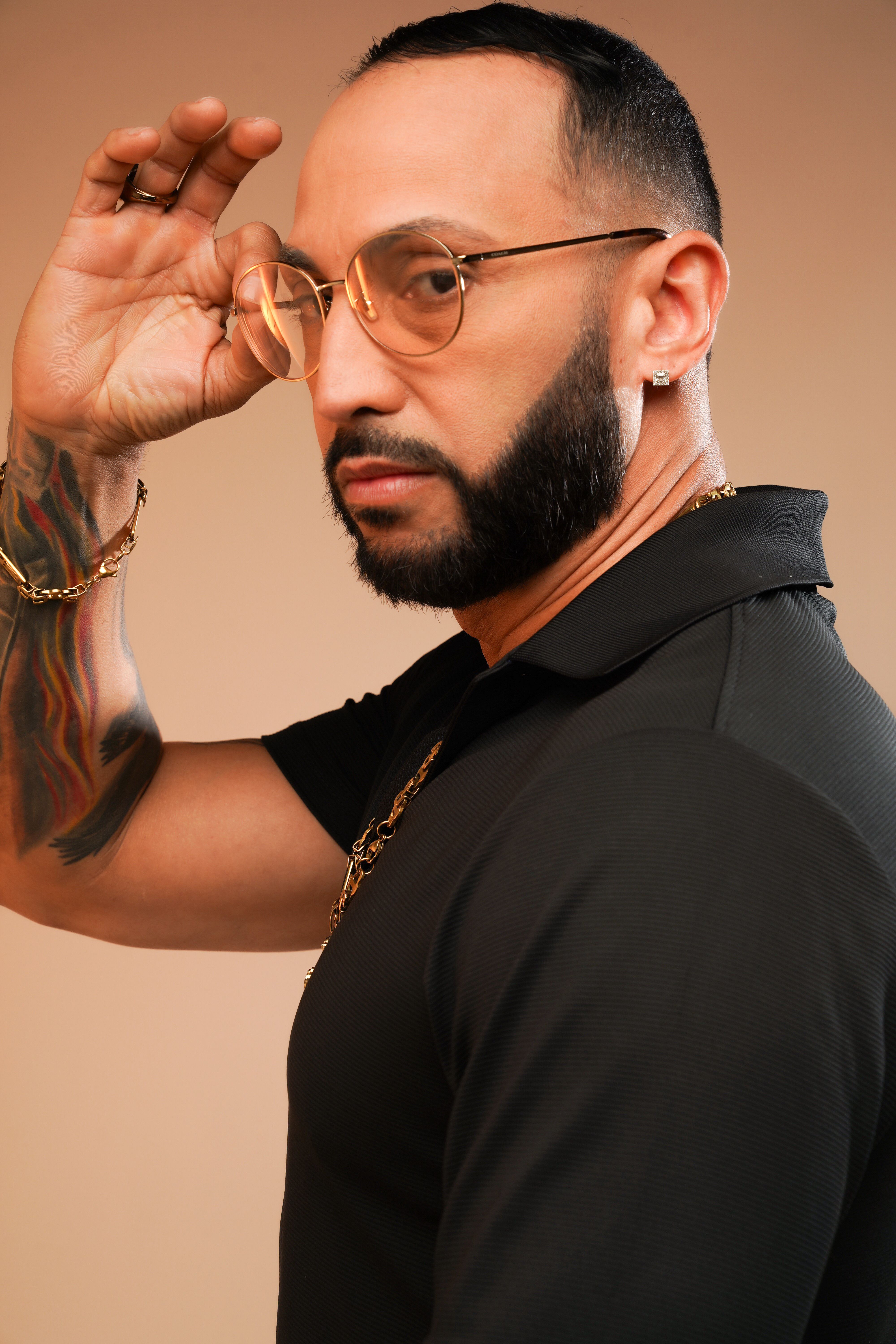 A confident man with eyeglasses and a beard adjusts his eyewear in a modern portrait.