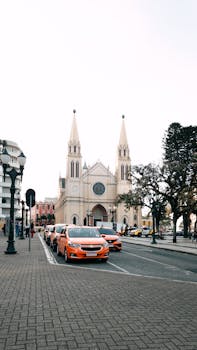 Historic cathedral in Curitiba with vibrant city street and cars, capturing urban life.