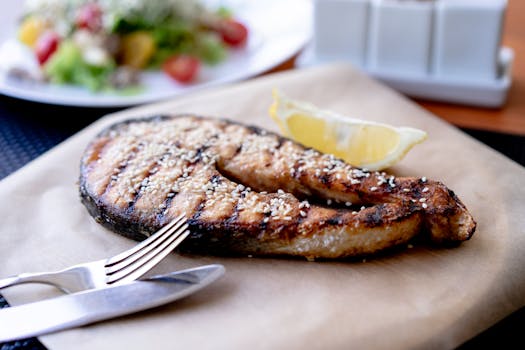 Delicious grilled salmon steak garnished with sesame seeds and lemon wedge, perfect for healthy eating.