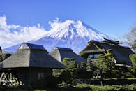 在晴朗的日子里，以富士山为背景的传统草帽房屋构成了一幅风景