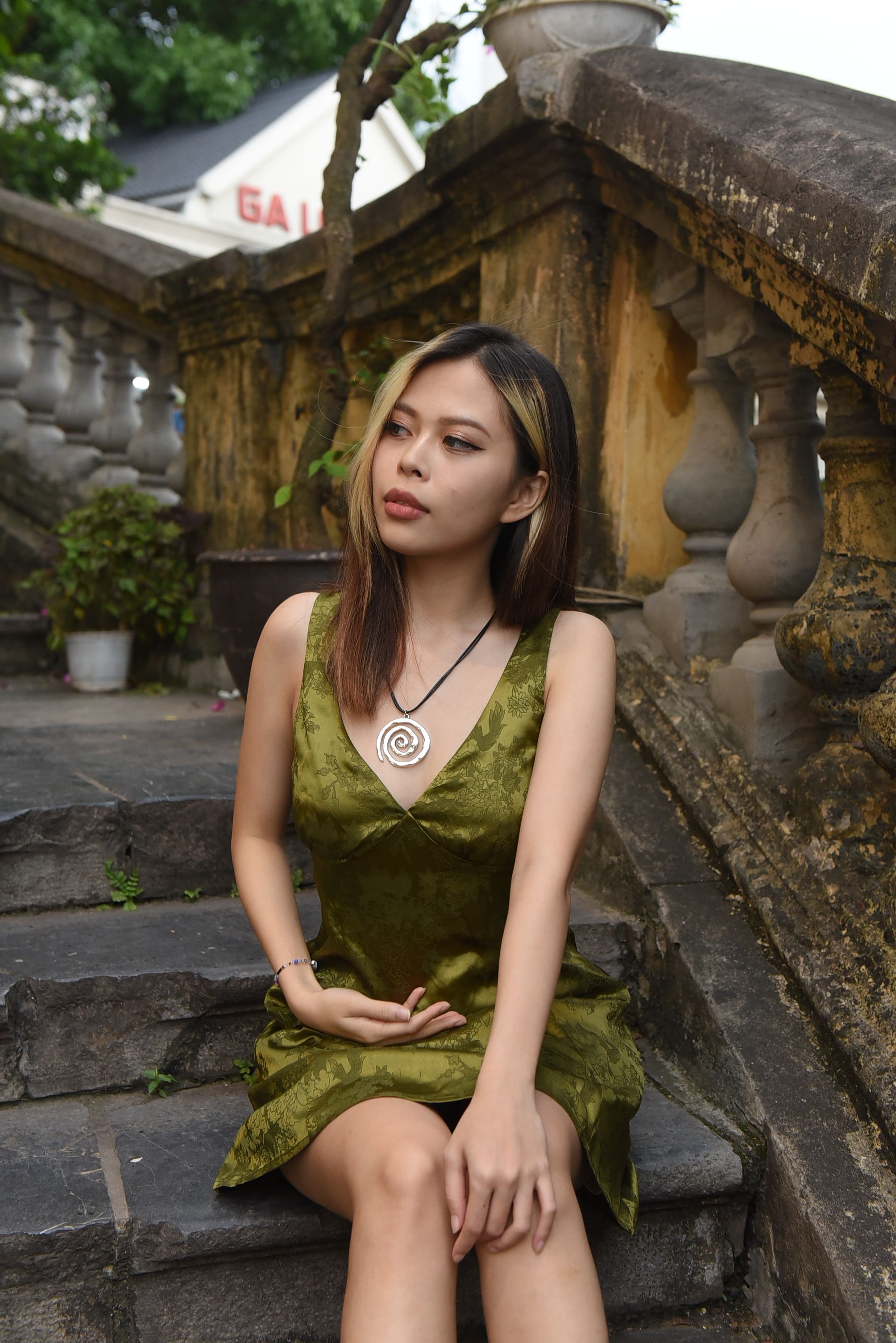 A woman in a green dress sitting on some steps · Free Stock Photo