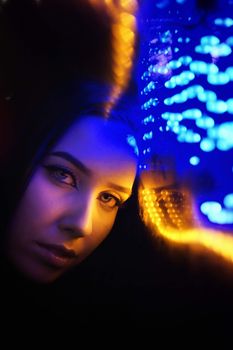 充满活力的霓虹灯蓝黄灯光下，女人的特写肖像被照亮