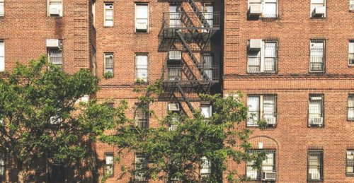 Free Facade of contemporary residential brick building with windows and fire escape ladders located in city on sunny day Stock Photo