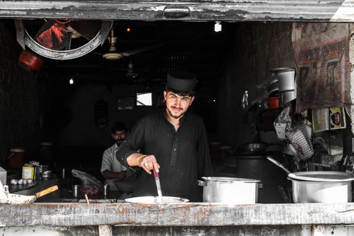 Free A man cooking in a traditional restaurant setting, showcasing cultural ambiance and culinary skills. Stock Photo