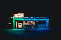 晚上，一辆摩托车停在霓虹灯闪烁的汉堡店外，色彩鲜艳