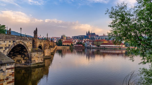Beautiful sunset view of Charles Bridge over the Vltava River in Prague, highlighting historic architecture and reflections.