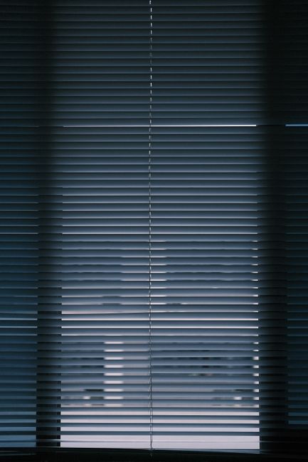 A vertical interior shot of closed window blinds creating a moody atmosphere.