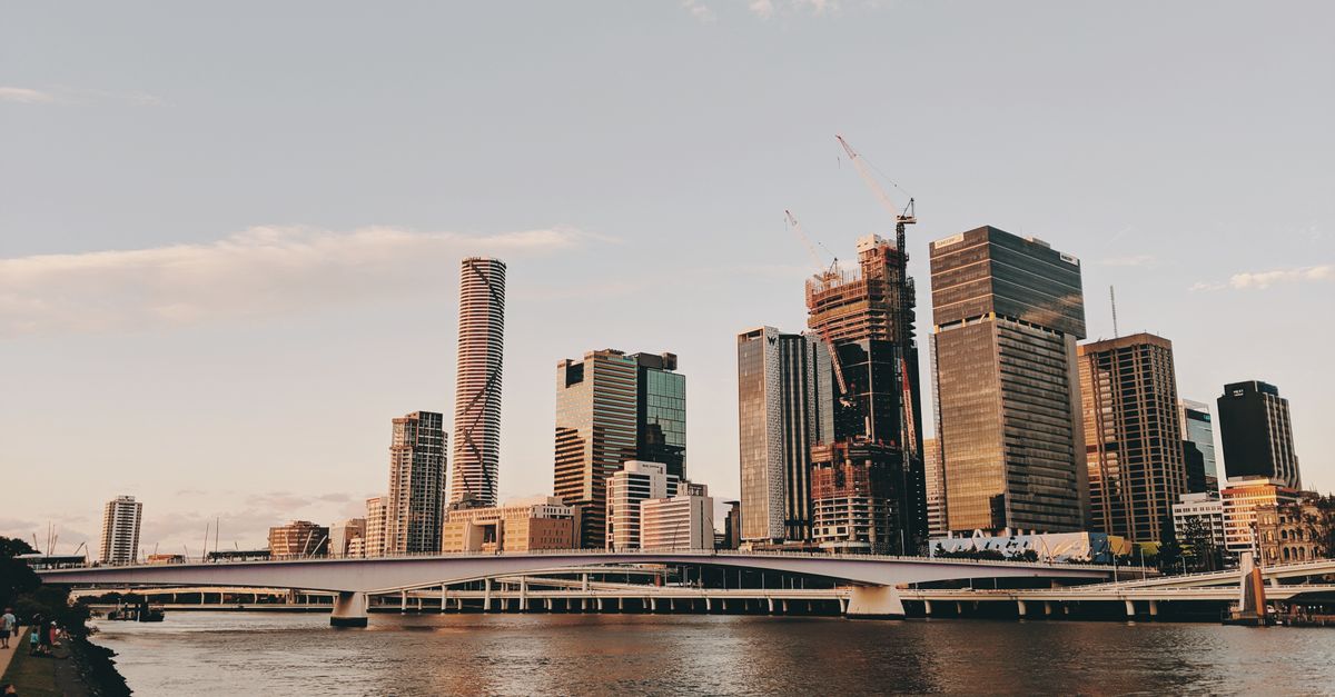 Stunning Brisbane skyline captured at sunset with the river in the foreground, showcasing urban architecture.