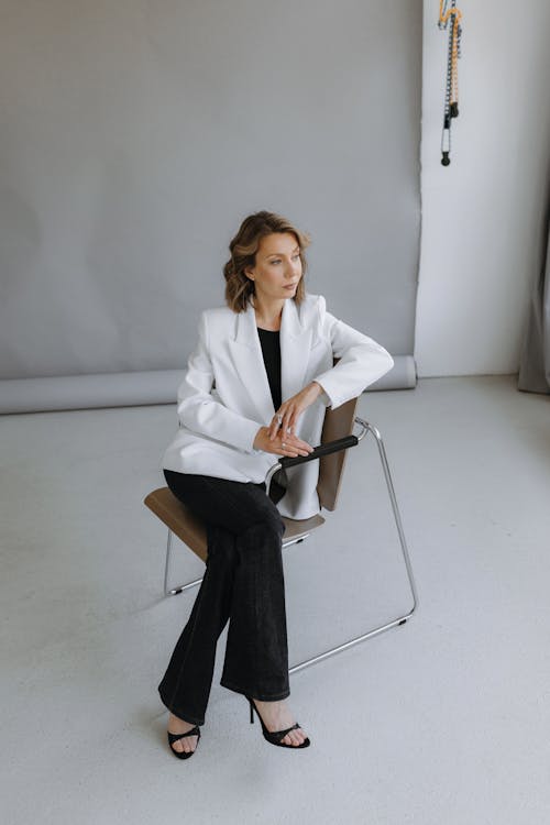 A woman in a white blazer sitting on a chair