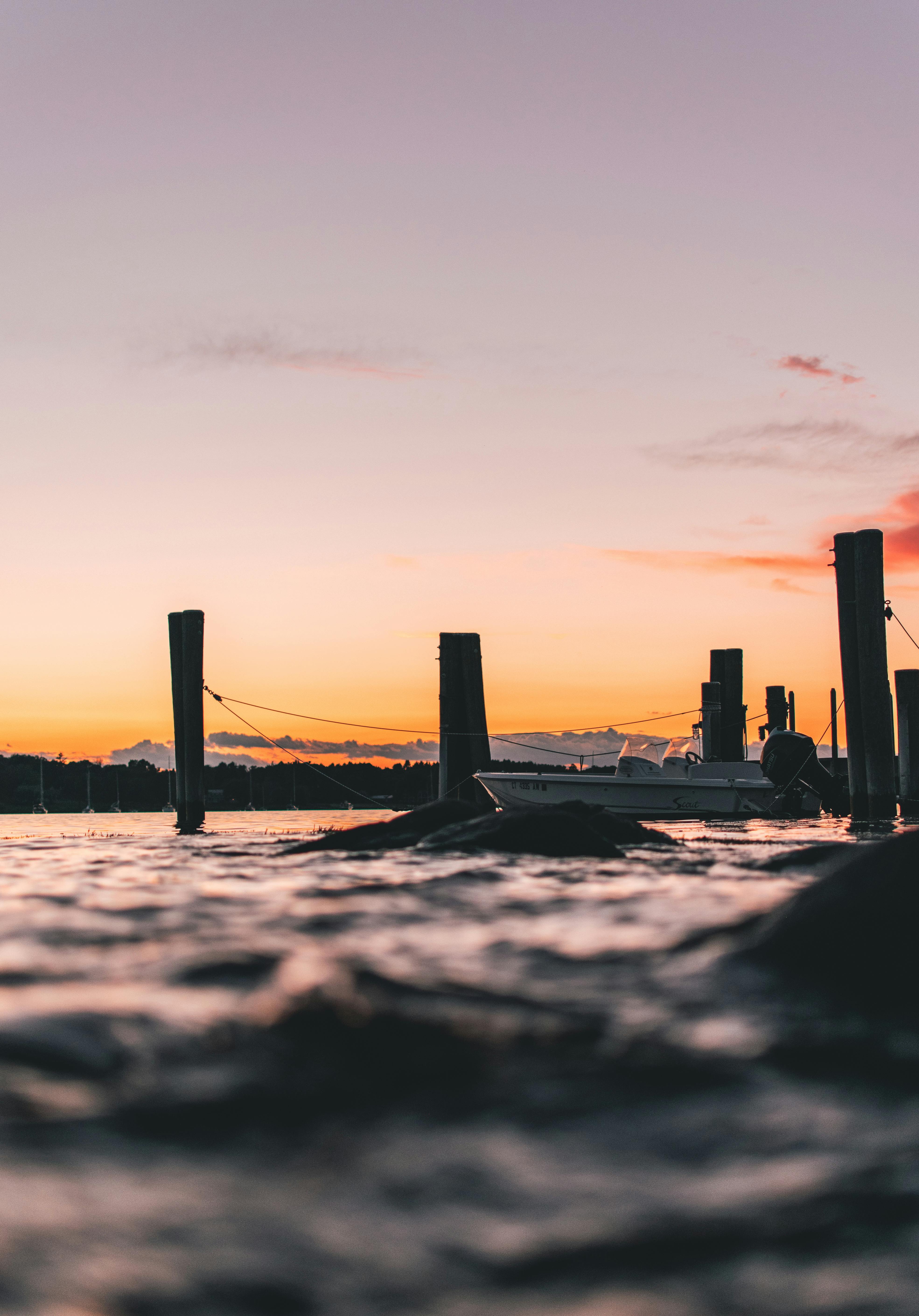 日落时分，一艘船漂浮在平静的水面上，天空充满活力，构成一幅宁静的场景