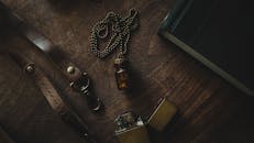 乡村静物以复古小瓶项链、打火机和木制桌子上的皮革表带为特色