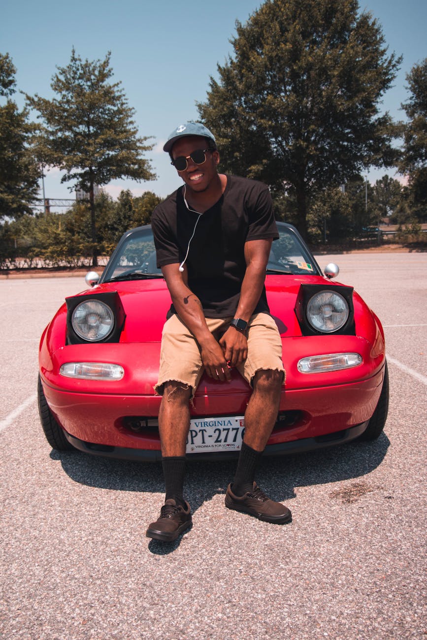 Photo of Man Sitting on Car Hood.