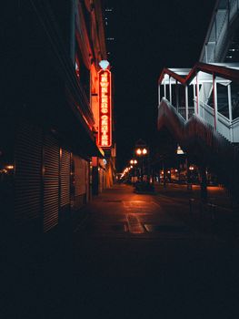 A vibrant urban street scene at night with neon signs and city lights creating a moody atmosphere.