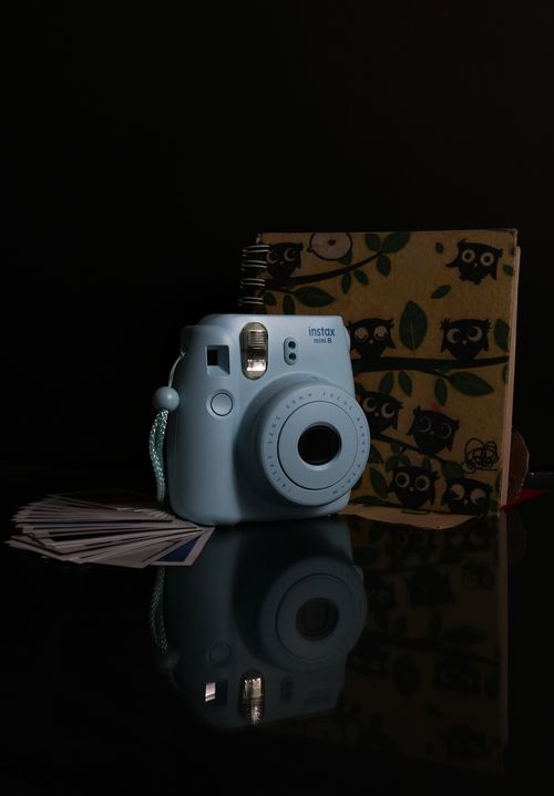 Free A charming blue Instax camera sits alongside a whimsical owl pattern box, perfect for capturing memories. Stock Photo