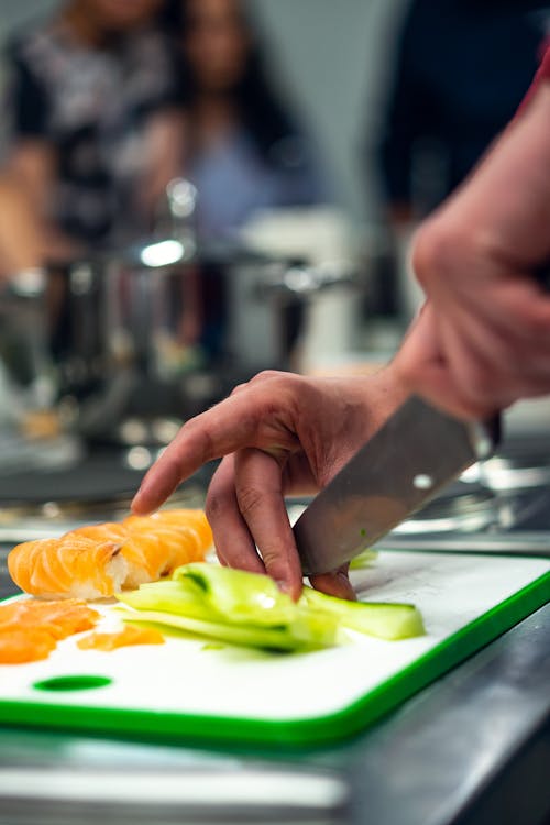 Free Selective Focus Photo of Person Slicing Vegetable on Chopping Board Stock Photo