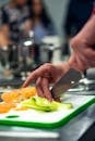 Selective Focus Photo of Person Slicing Vegetable on Chopping Board