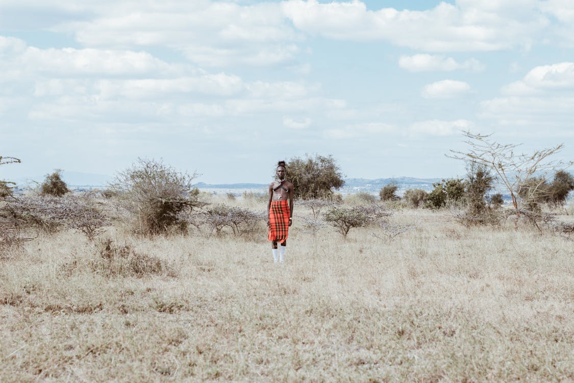 Free Photo of Man in Red and White Lungi Skirt Standing on Grass Field Stock Photo