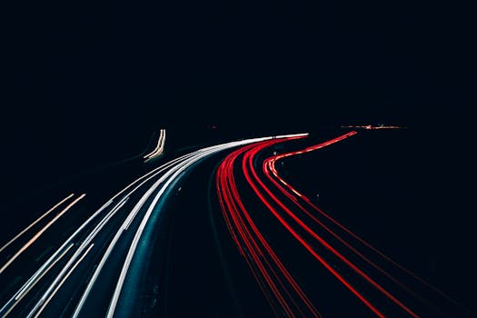 Long exposure shot capturing light trails of vehicles on a highway at night, creating dynamic patterns.
