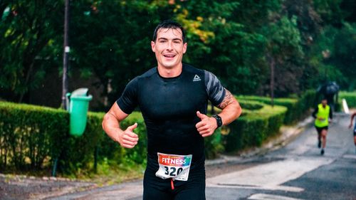 Free A fit male runner participating in an outdoor marathon during rainy conditions. Stock Photo