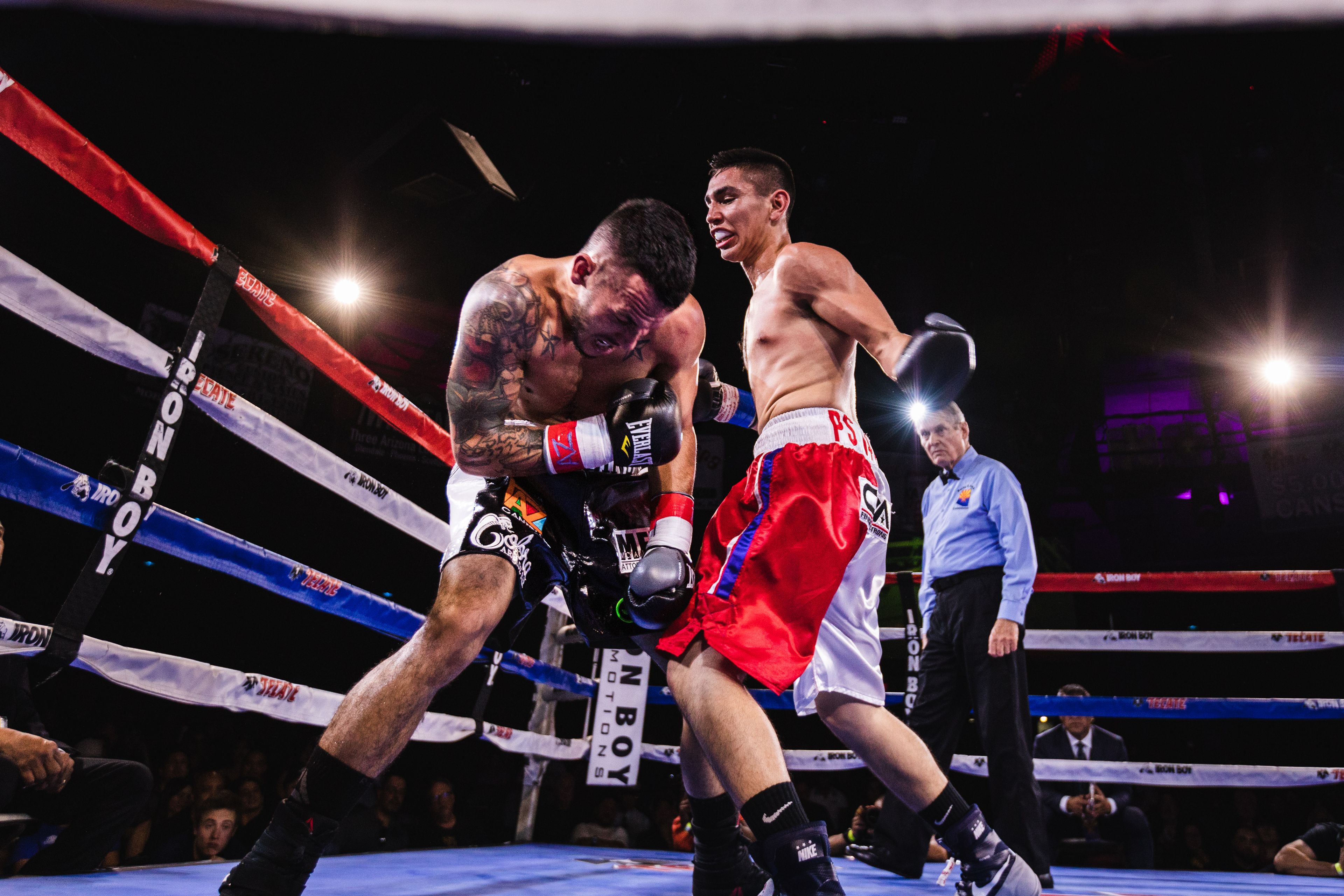 Two men fighting in a boxing ring — low angle action shot with referee