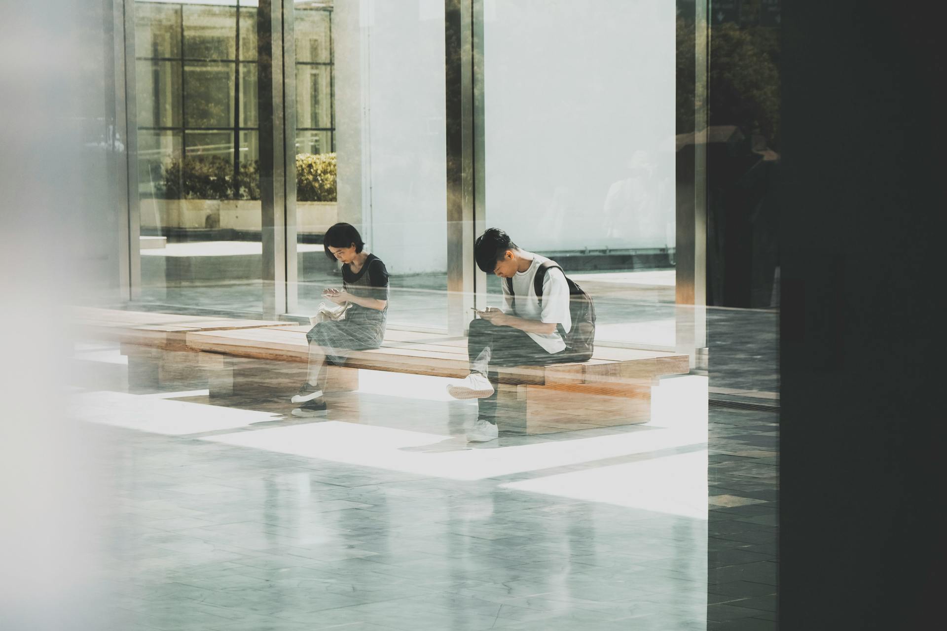 A serene view of people sitting and reading at a modern glass building in Taipei City, Taiwan.