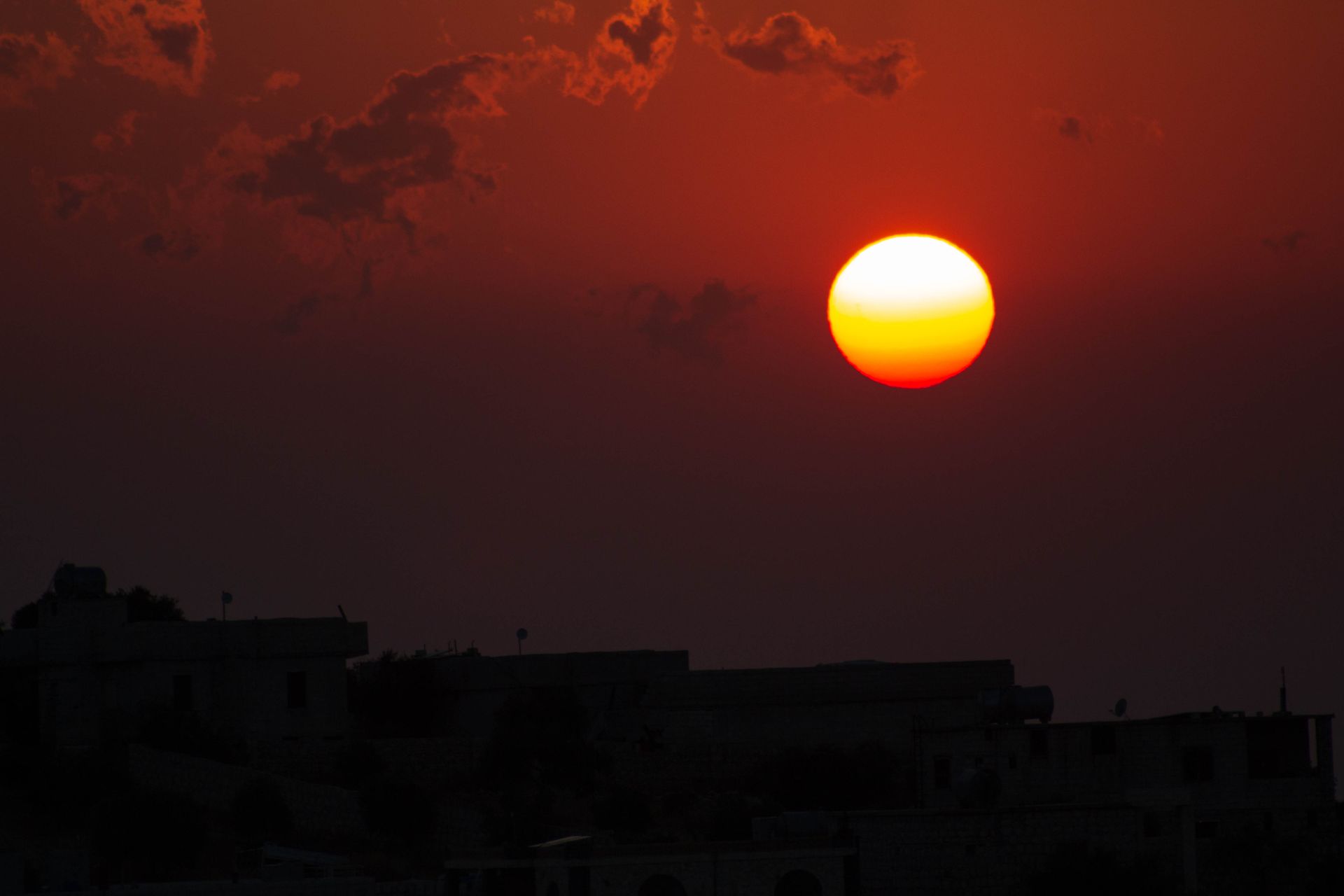 Stunning sunset over Aaqrabâte, Idlib Governorate, casting silhouettes with vibrant colors.