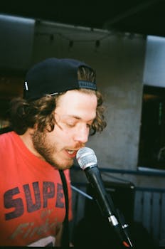 年轻的男歌手在户外热情地用麦克风表演