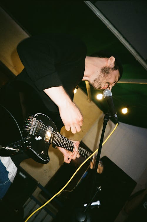 Low-Angle Photo of Man Singing While Playing Electric Guitar