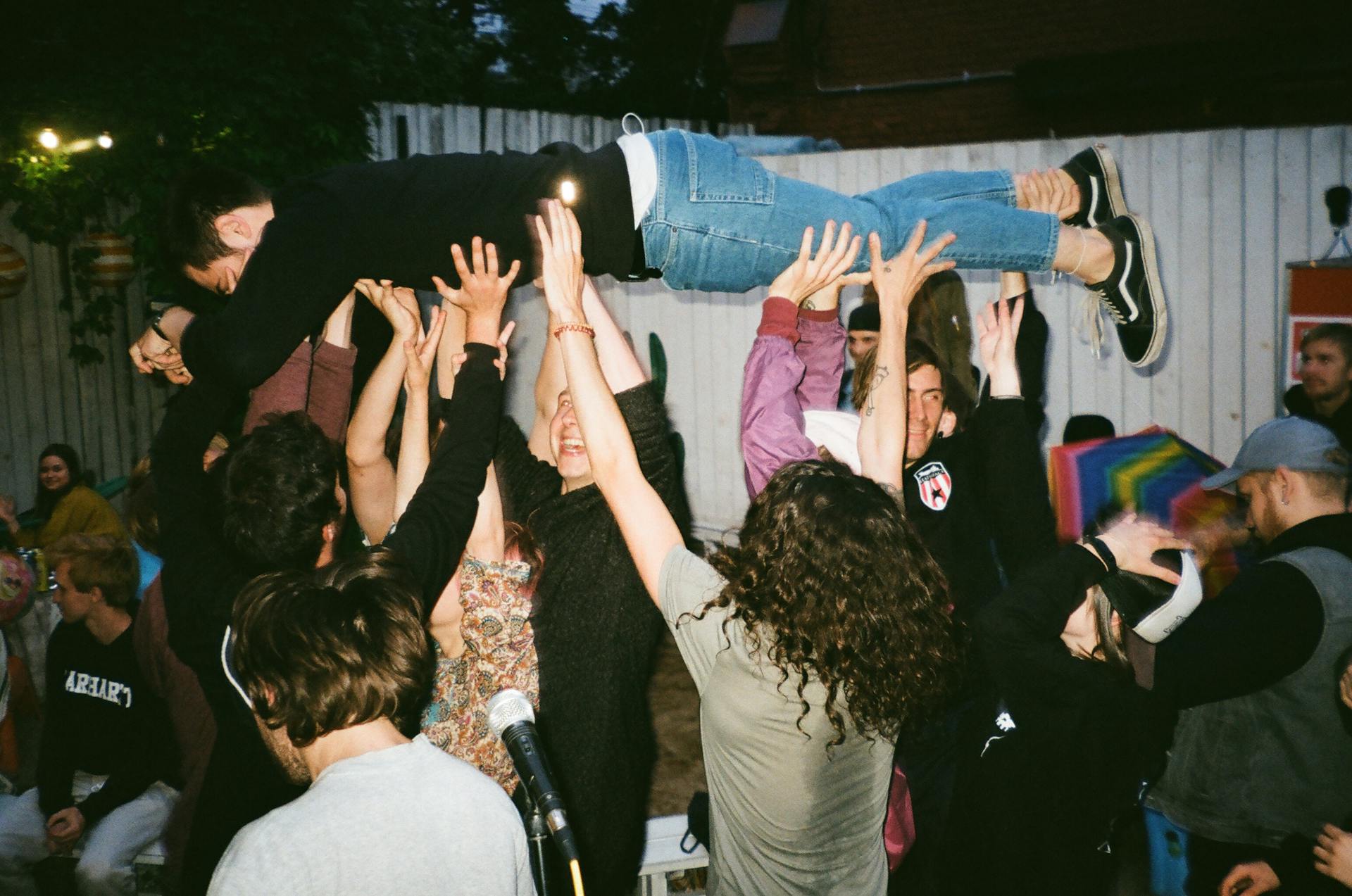 Group of people joyfully lifting a friend during an outdoor party.