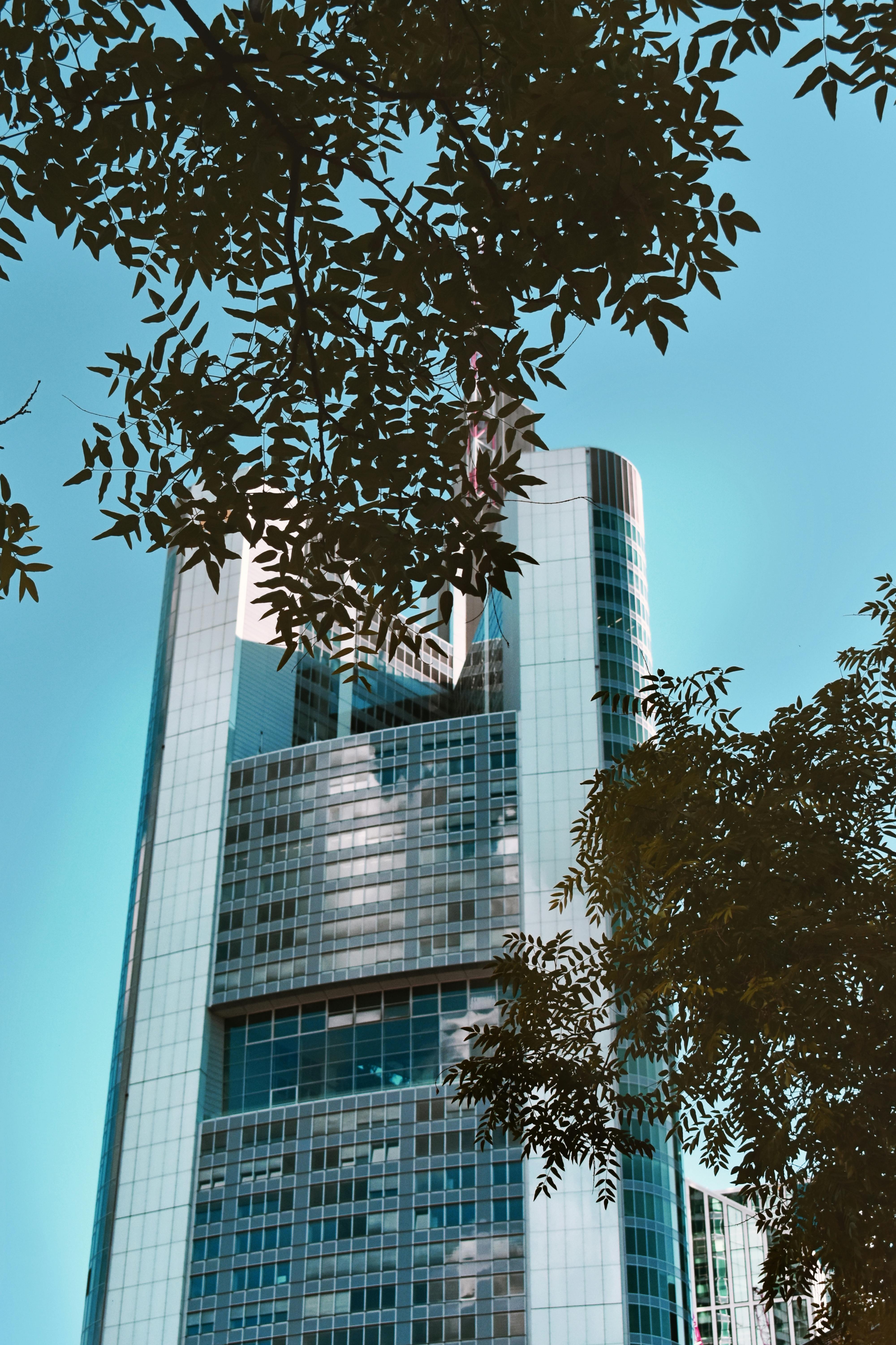 一座被郁郁葱葱的绿叶环绕的当代摩天大楼，矗立在法兰克福，展现了现代建筑设计