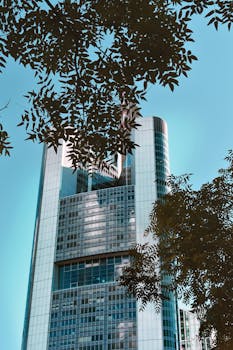 一座被郁郁葱葱的绿叶环绕的当代摩天大楼，矗立在法兰克福，展现了现代建筑设计