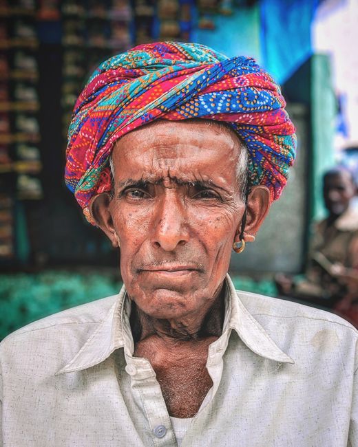Close-up portrait of an elderly Indian man wearing a vibrant turban outdoors.