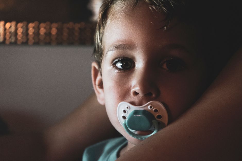 Criança pequena com chupeta, retrato em close com iluminação suave