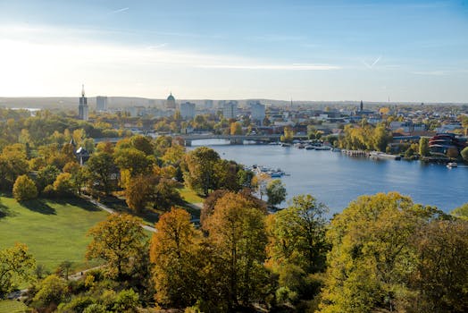 从空中俯瞰，河边郁郁葱葱的公园背后是秋天的城市天际线