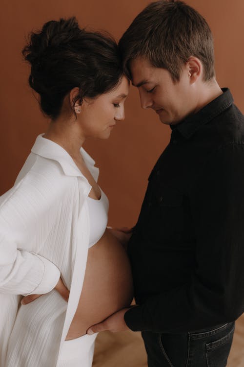 A pregnant woman and her husband are standing next to each other