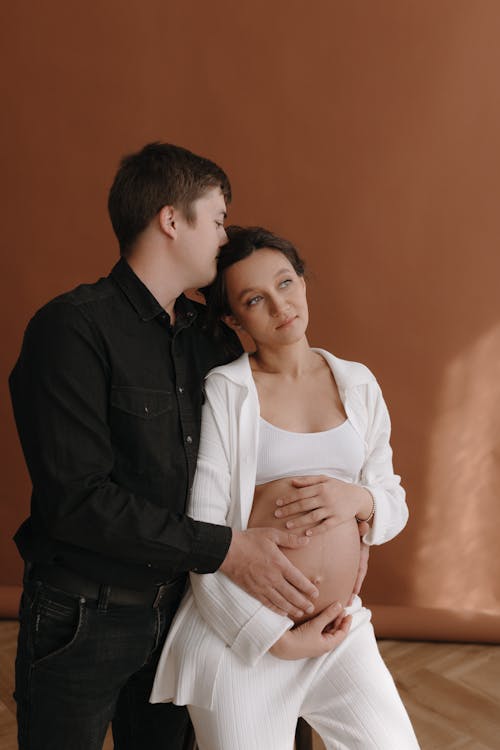 A pregnant woman and her husband are posing for a maternity photo