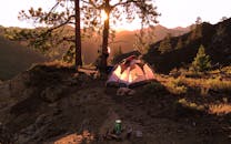 帐篷坐落在森林覆盖的山区，在日出时分捕捉户外露营的宁静之美