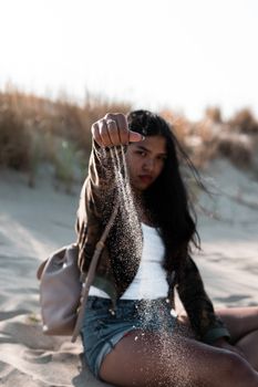 A young woman enjoying a sunny day, sitting on the sandy shores of Nida Beach in Lithuania.