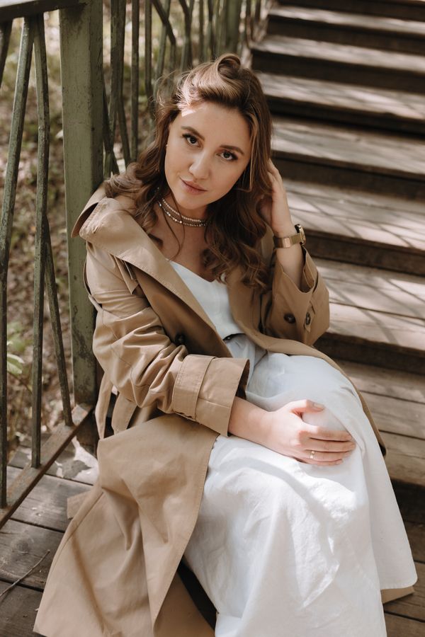 Woman sitting in a dress and trench coat