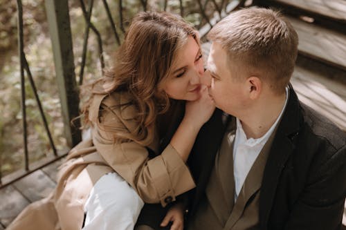 A couple sitting on a wooden bridge in the woods