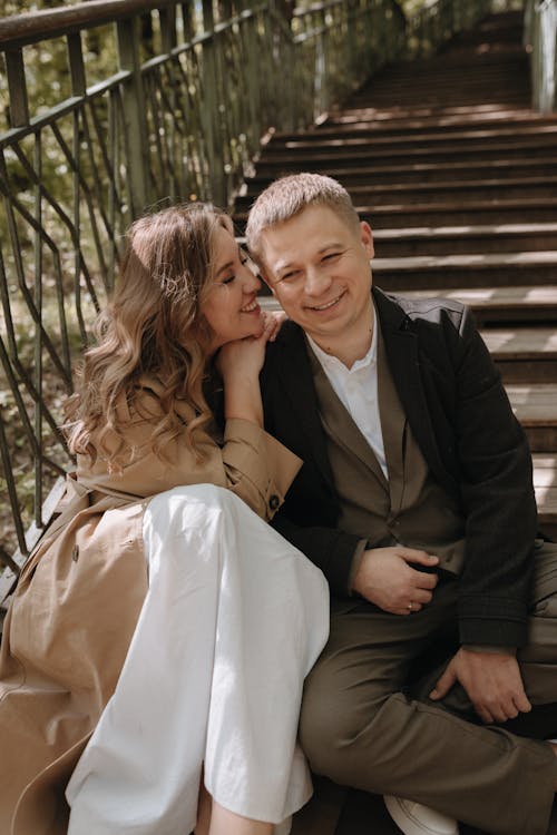 A couple sitting on the stairs in front of a tree