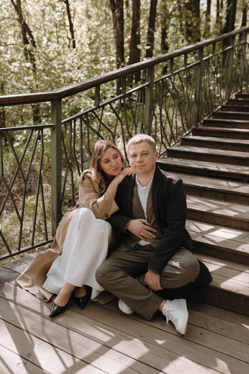 A man and woman sitting on the stairs in the woods