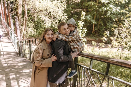 A family is standing on a bridge in the woods