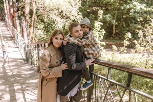 A family is standing on a bridge in the woods