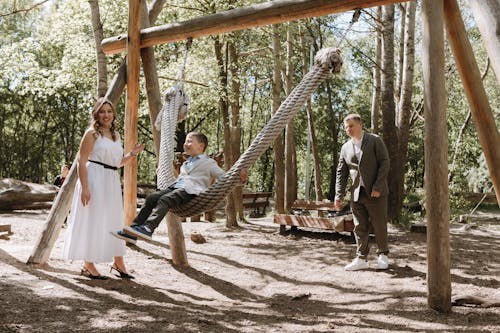 A family is sitting on a swing in the woods